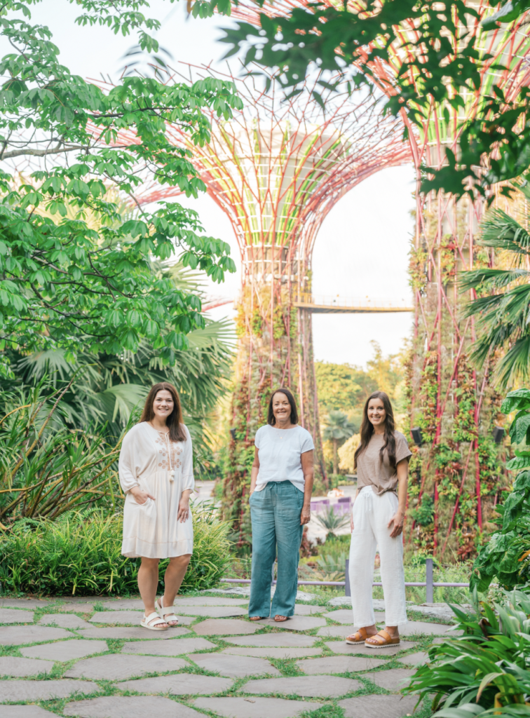 three women standing in lush garden